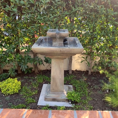 formal stone fountain at edge of garden