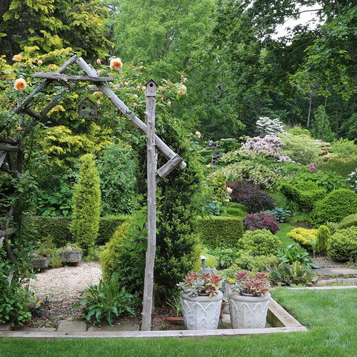 Fred Bland garden featuring rustic arborb coverd with yellow climbing roses